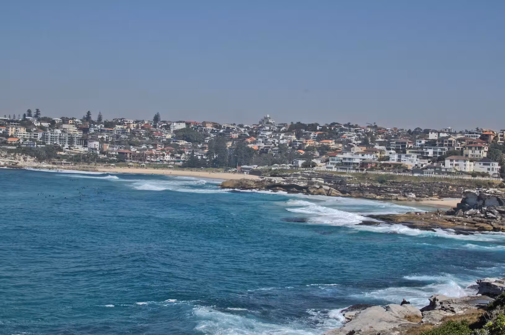 Turquoise waves lap toward the houses on the hillside above the beach.