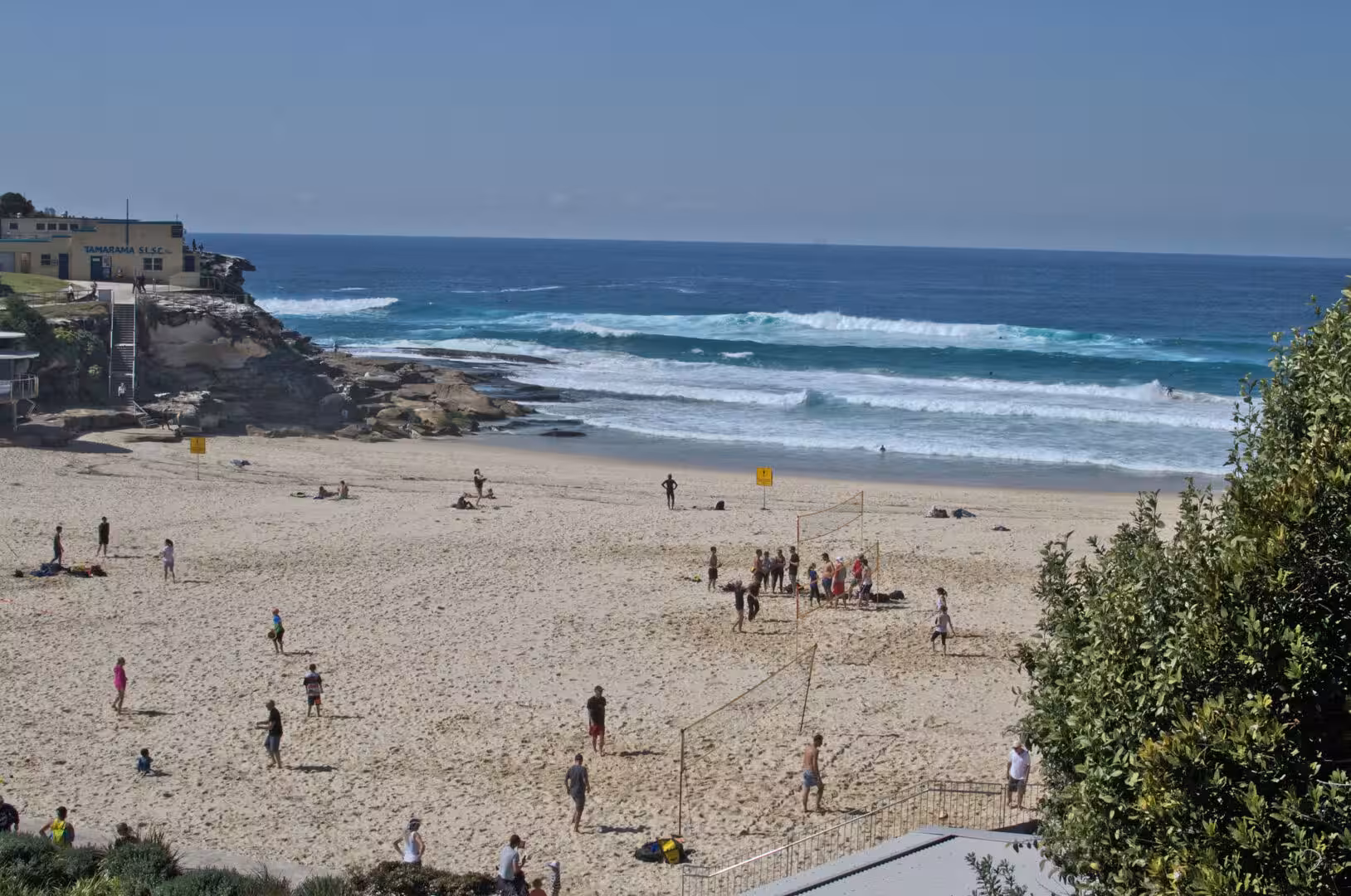 People play volleyball on the sand beneath breaking waves at Tamarama beach.
