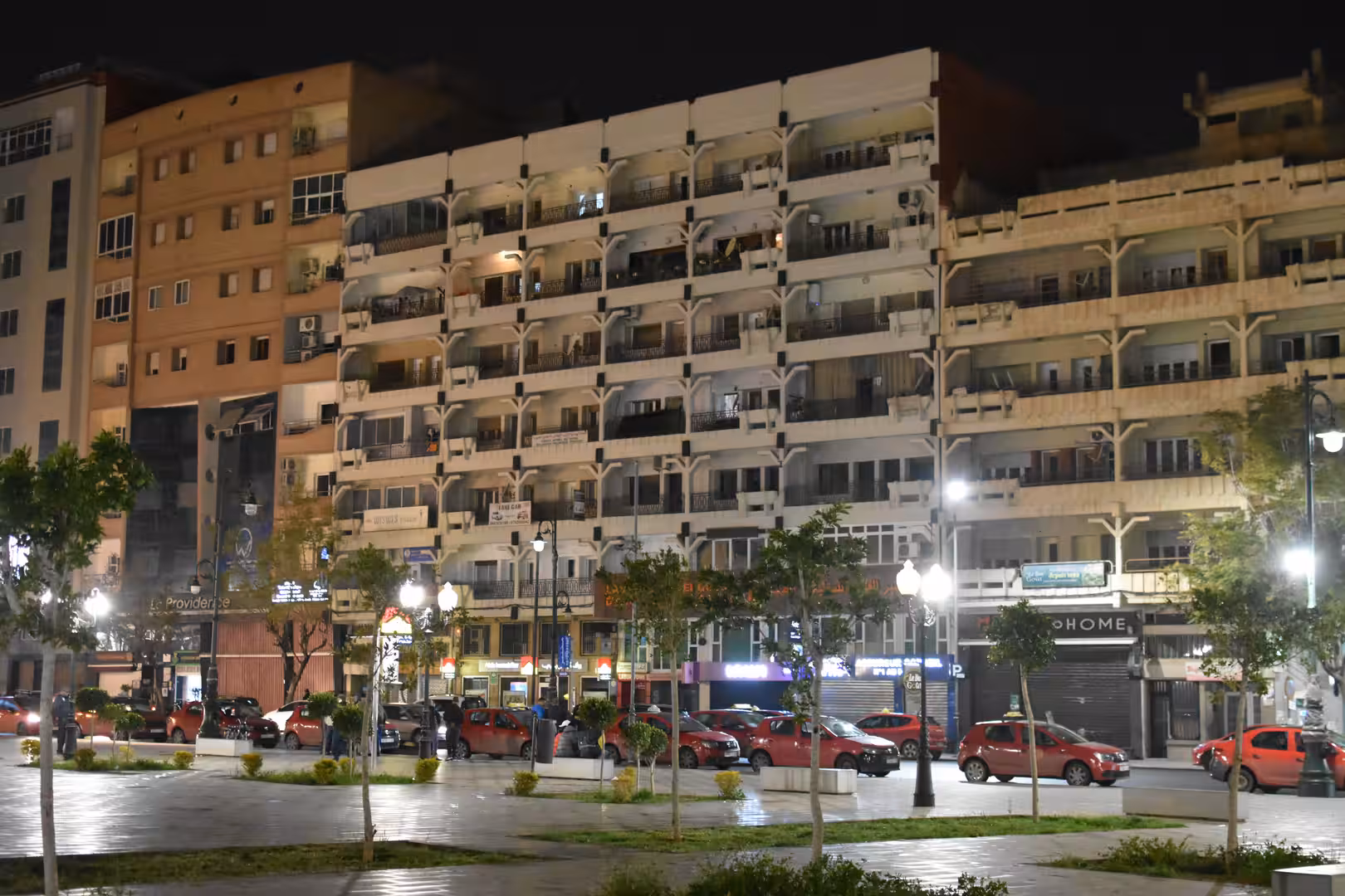 Apartment buildings and illuminated streets surrounding a public square after dark.
