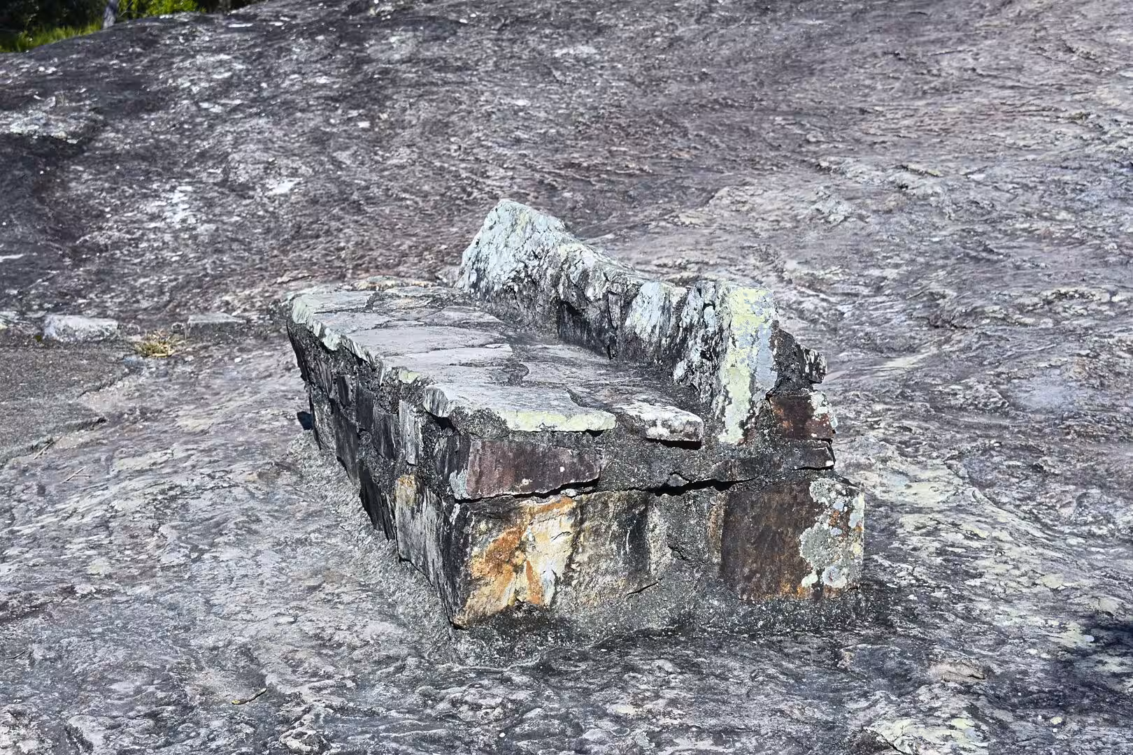 An old lichen-covered stone structure rests on a rocky granite surface.