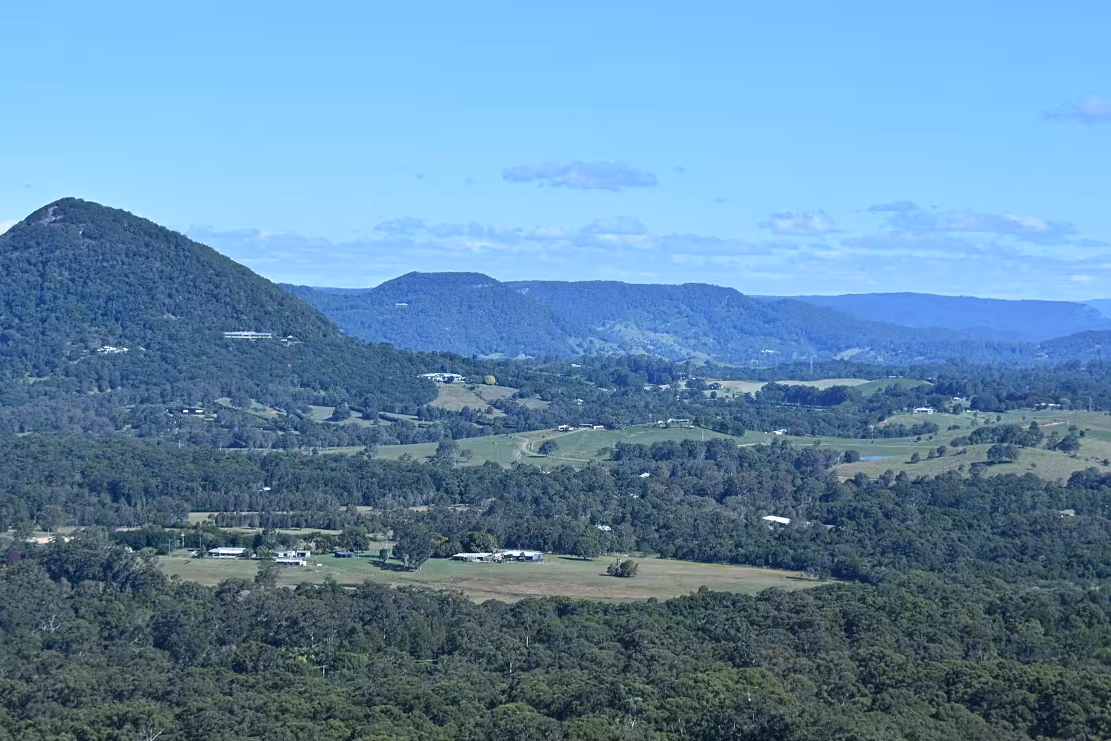A wide view of tree-covered hills stretching toward distant blue mountains.