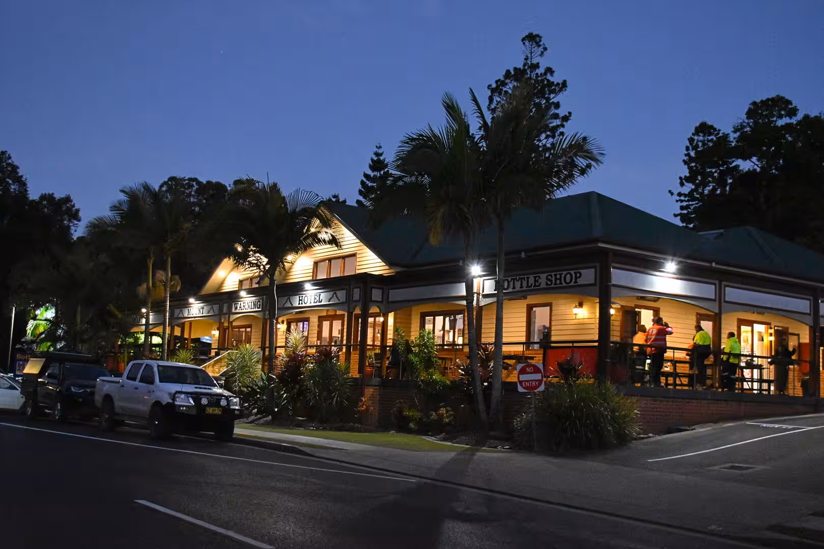 A timber country hotel with a veranda lights up at night.
