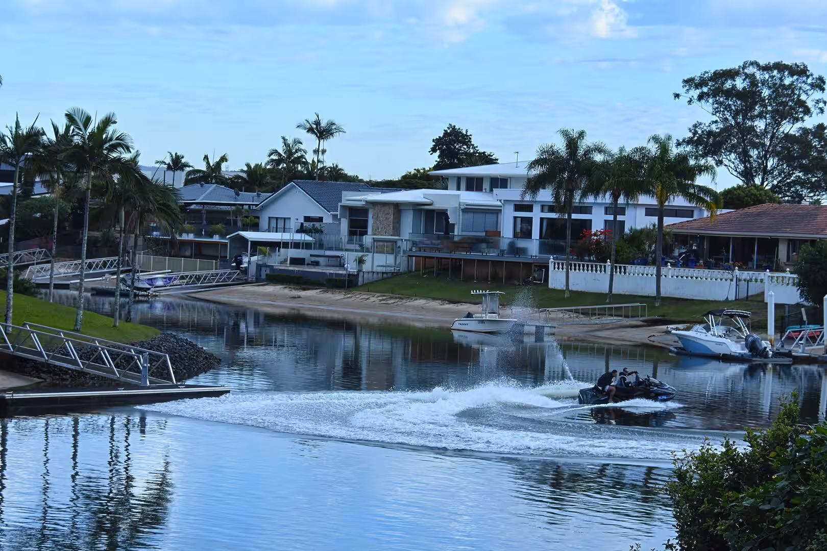 A jet ski races across the water in front of canal-front homes.