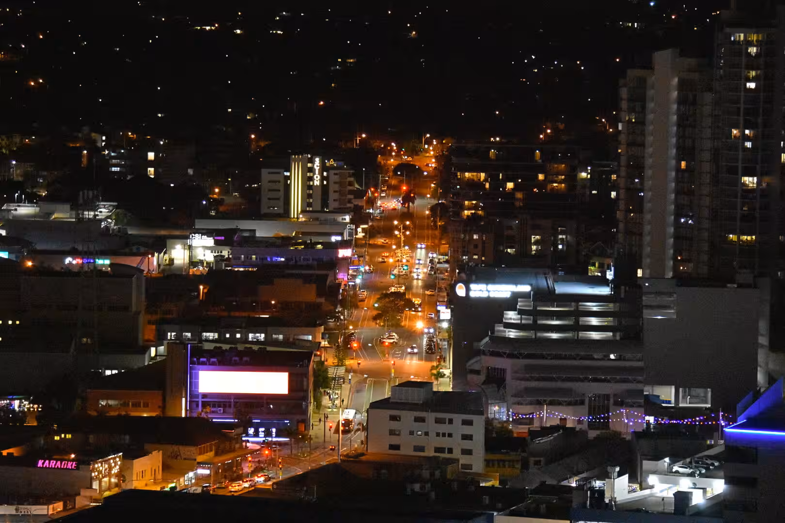 A lit main street runs between neon signs and a curved-roof building.