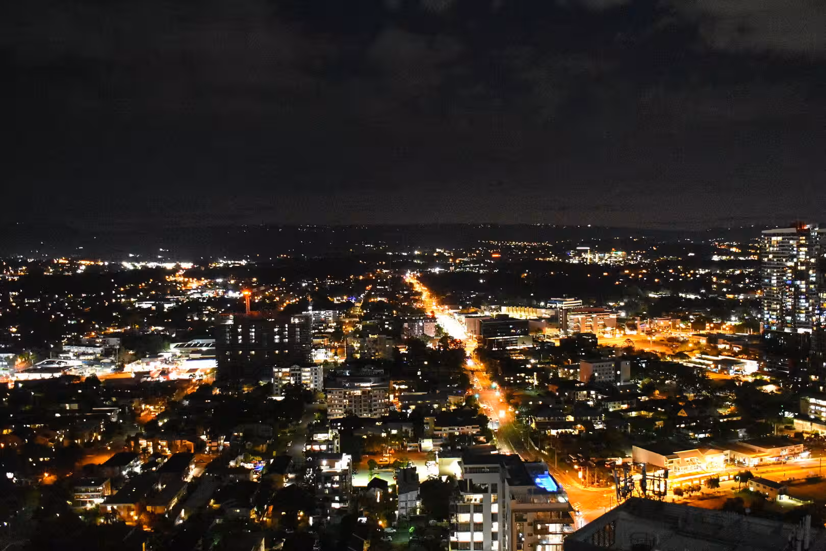 A sprawling city shines with warm lights under a dark night sky.