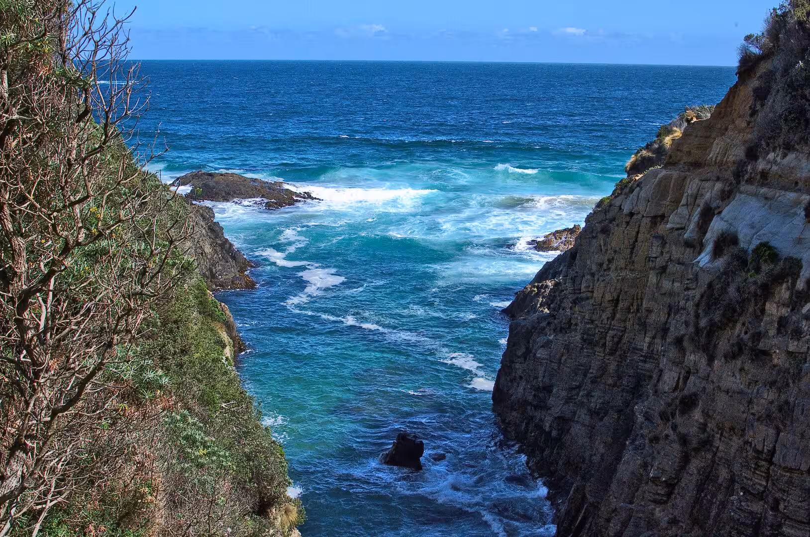 A sheltered cove of turquoise water is cradled between steep rocky cliffs.