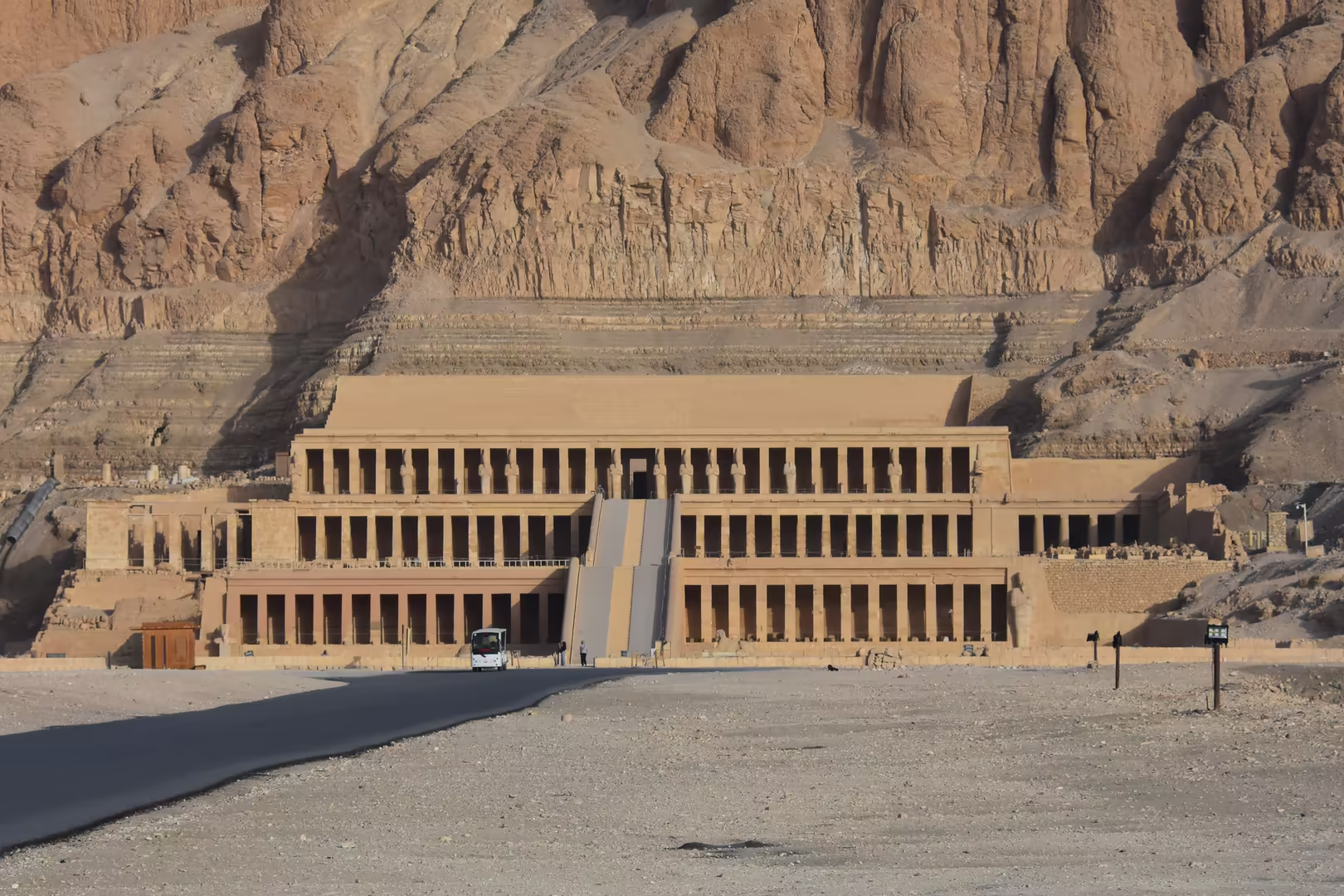 Tiered colonnades of an ancient temple hug the sheer cliff face.