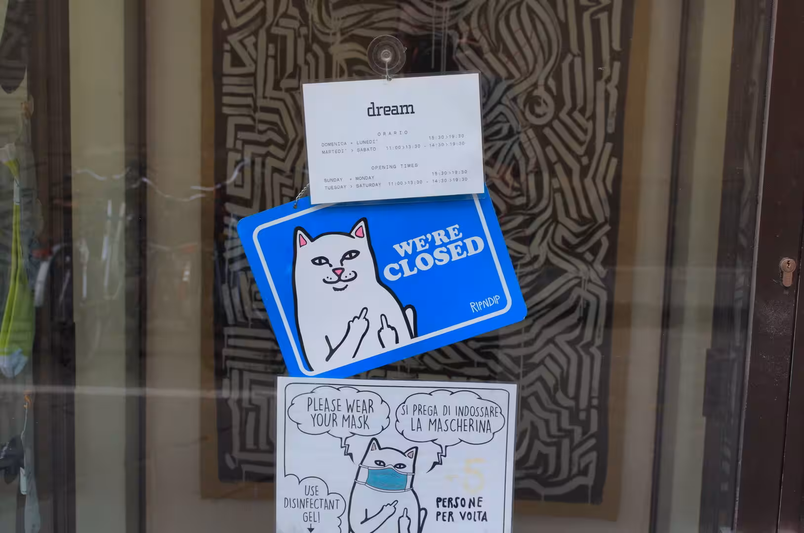 A cheeky white-cat closed sign hangs amid face-mask notices.