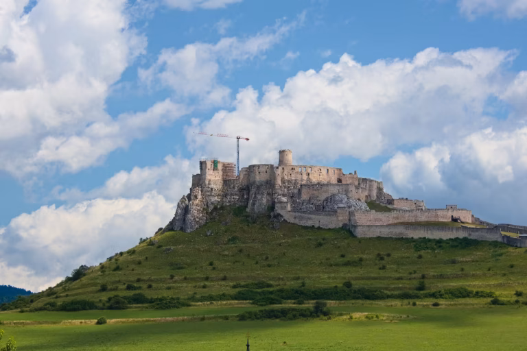 Spiš Castle spreads its long walls and towers across a broad green hill.